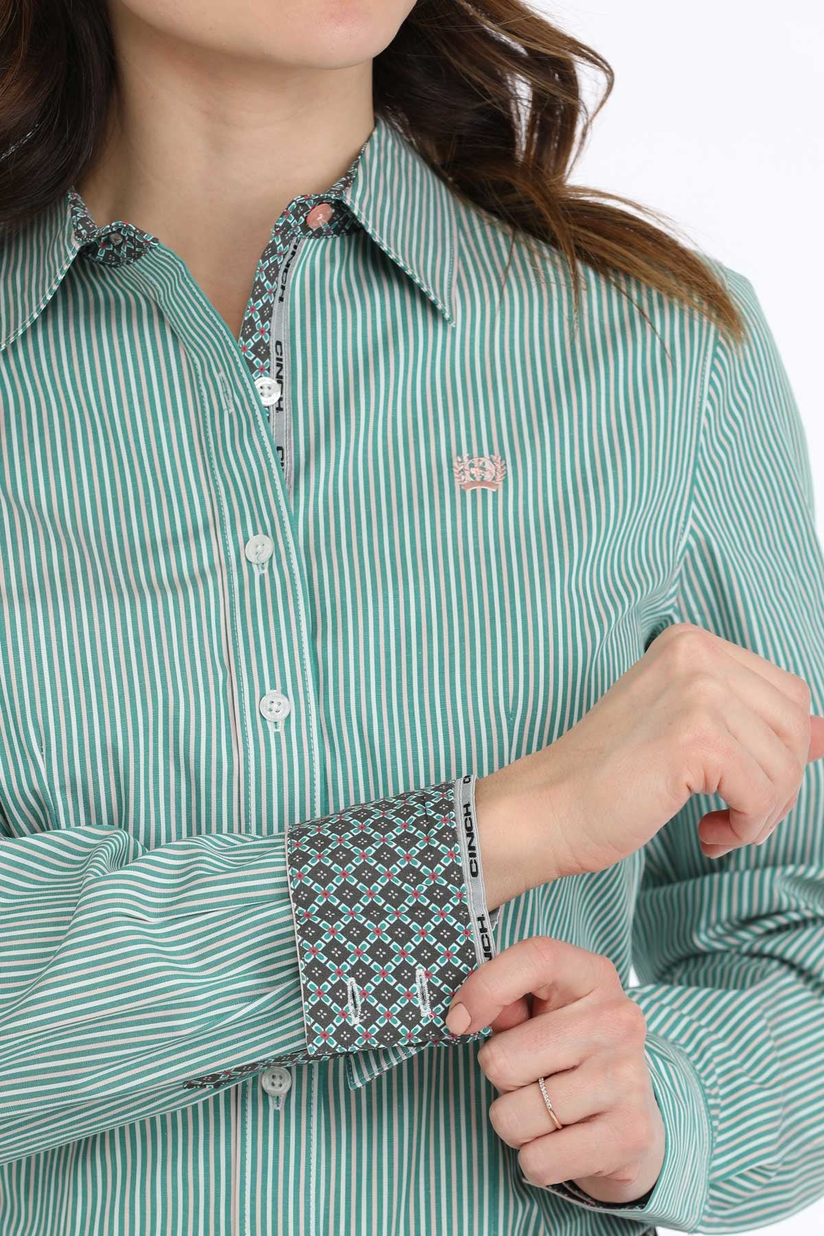 Cinch Women's Stripe Button-Down L/S Western Shirt. Woman wearing a green patterned shirt and blue jeans with a decorative belt.