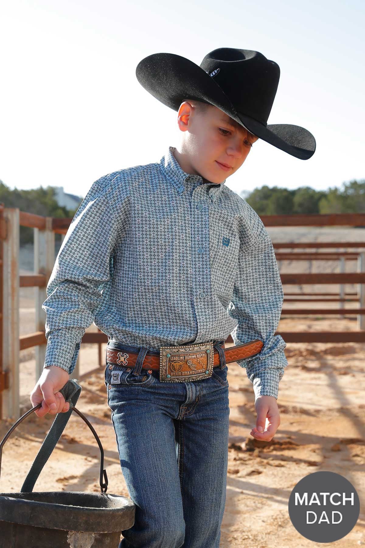 Cinch Boy's Geometric Print L/S Western Shirt. Young boy in cowboy attire holding a bucket in an outdoor setting.
