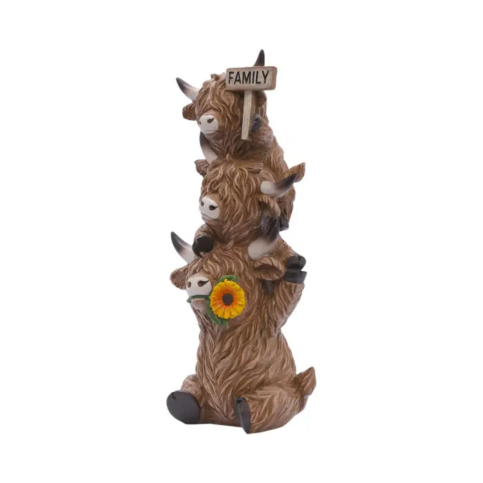 A decorative figurine of four stacked brown highland goats on a white background. The bottom goat holds a yellow sunflower, and the top goat holds a small wooden sign that reads 'FAMILY'.