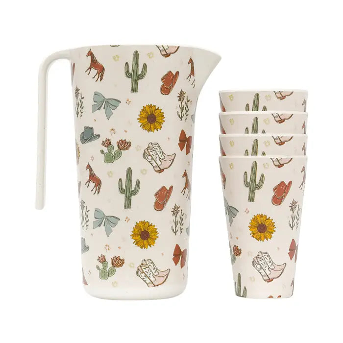 A ceramic pitcher and matching four tumblers with a western-themed print featuring cacti, cowboy boots, sunflowers, and hats on an off-white background.