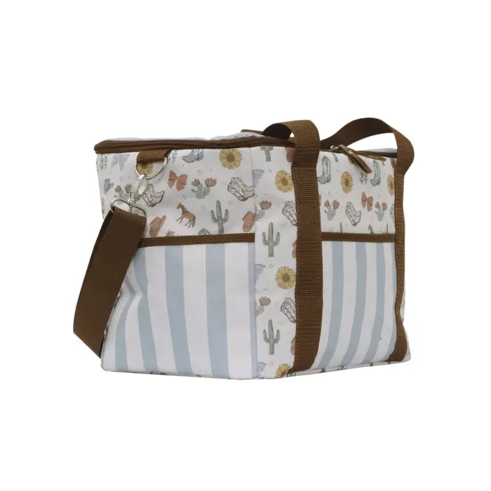A rectangular tote bag with a split design, featuring a brown and white striped lower half and a white upper half with a desert pattern of cacti, butterflies, and sunflowers. It has brown webbing handles and a matching shoulder strap, shown on a plain white background.