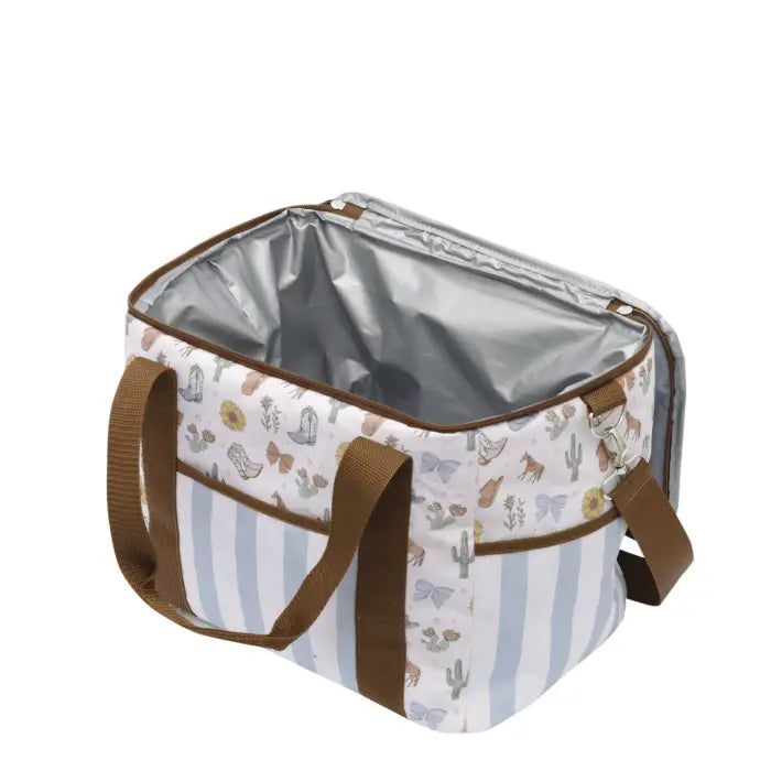 A square-shaped cooler bag with a white and light blue vertical stripe pattern on one side, decorated with a western-themed print of cacti, boots, and horseshoes on the other side. It features brown handles, brown trim, and a silver reflective lining, shown open against a plain white background.