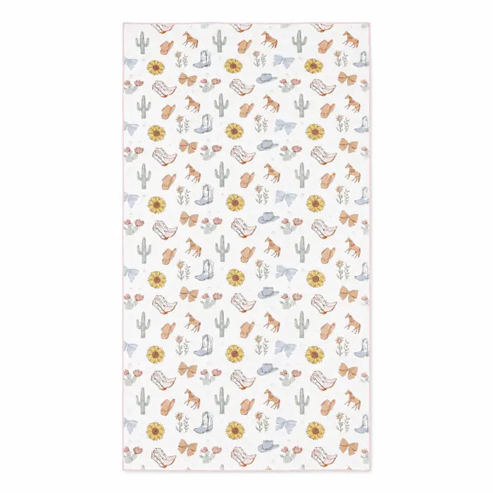 A rectangular fabric item, likely a baby blanket or towel, featuring a repeating western-themed pattern of cacti, horses, boots, hats, and flowers on a white background.