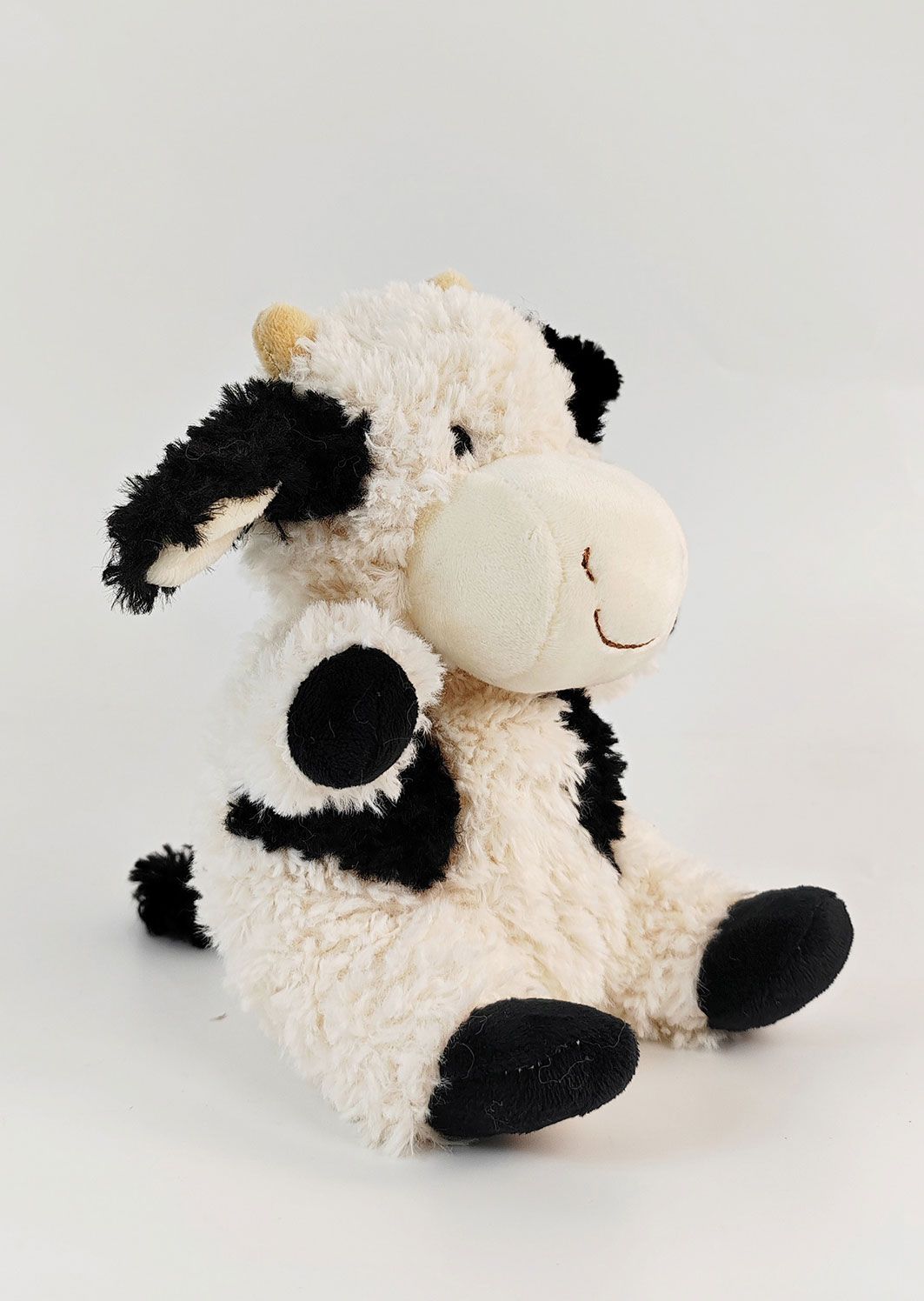 Plush cow toy with black and white pattern on a white background