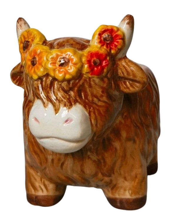 Ceramic cow figurine with floral crown on a white background