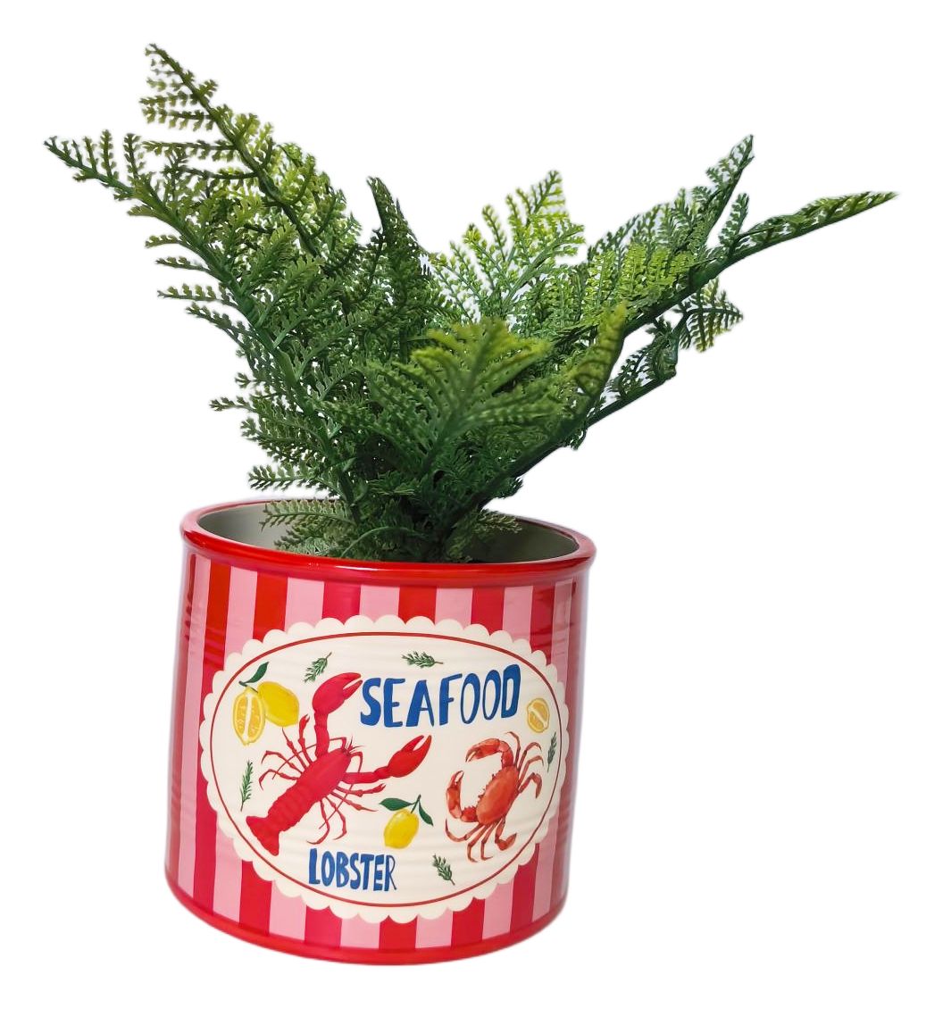 An artificial green fern plant in a cylindrical red and white striped tin planter with a 'Seafood Lobster' label illustration, set against a plain white background.