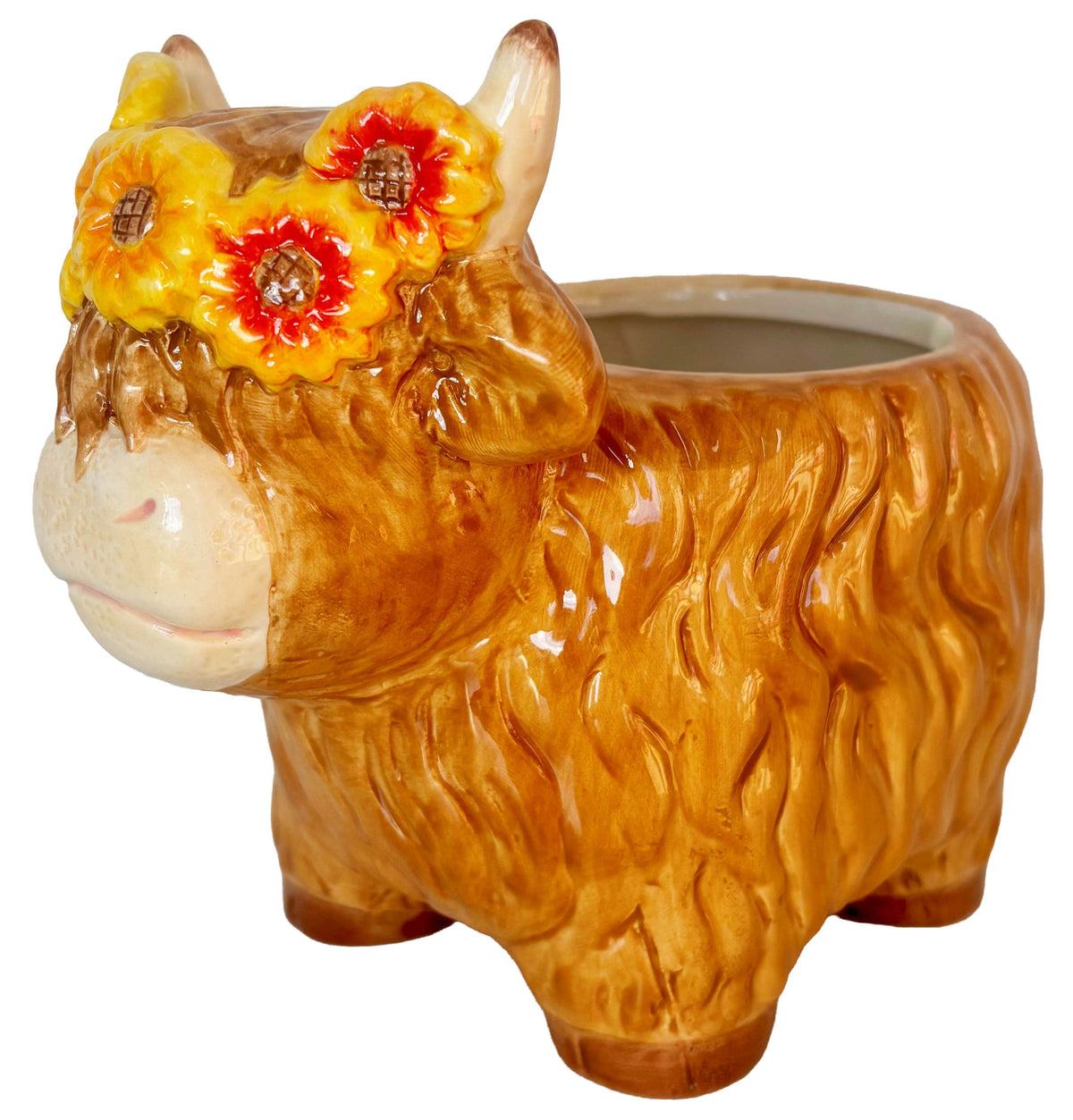 A ceramic Highland cow planter with a glossy brown and orange textured body, cream-colored face, and three yellow flowers with red centers on its forehead, shown on a white background.