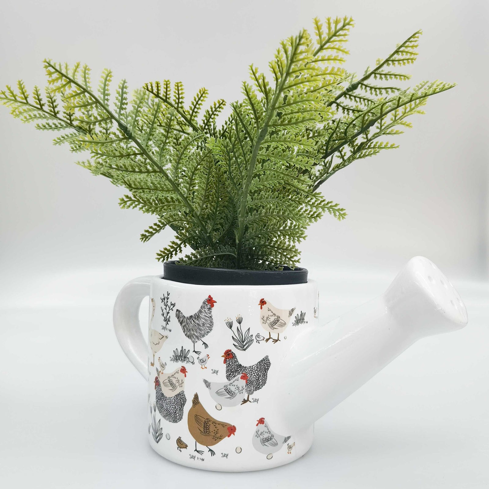 White ceramic teapot with chicken pattern on a white background