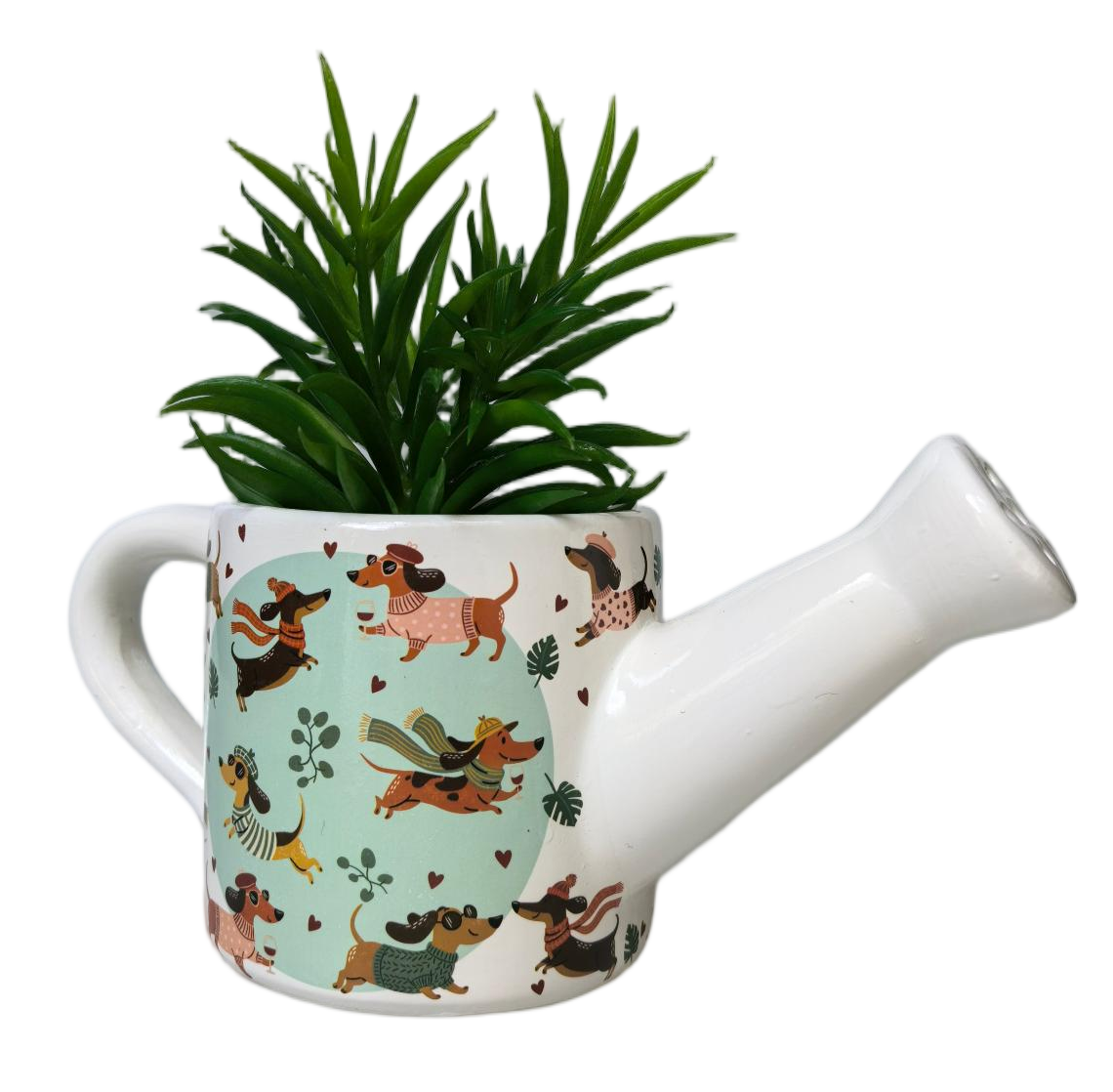A white ceramic watering can planter with a dachshund pattern, containing a green artificial plant, isolated on a white background.