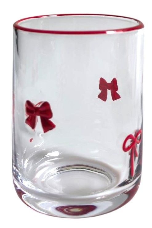 A clear glass tumbler with a thin red rim and red bow motifs printed on the side, shown against a plain white background.