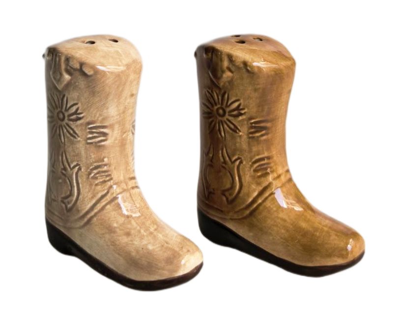 A pair of cowboy boot-shaped salt and pepper shakers with a glossy tan finish and carved western floral details, shown on a plain white background.