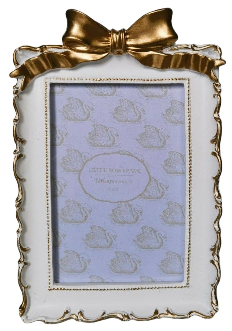A decorative picture frame with a white body, scalloped gold trim, and a large gold bow at the top. The frame is shown holding a lavender swan-patterned insert, with the text 'LOTTE BOW FRAME' and 'Ulm am Z.